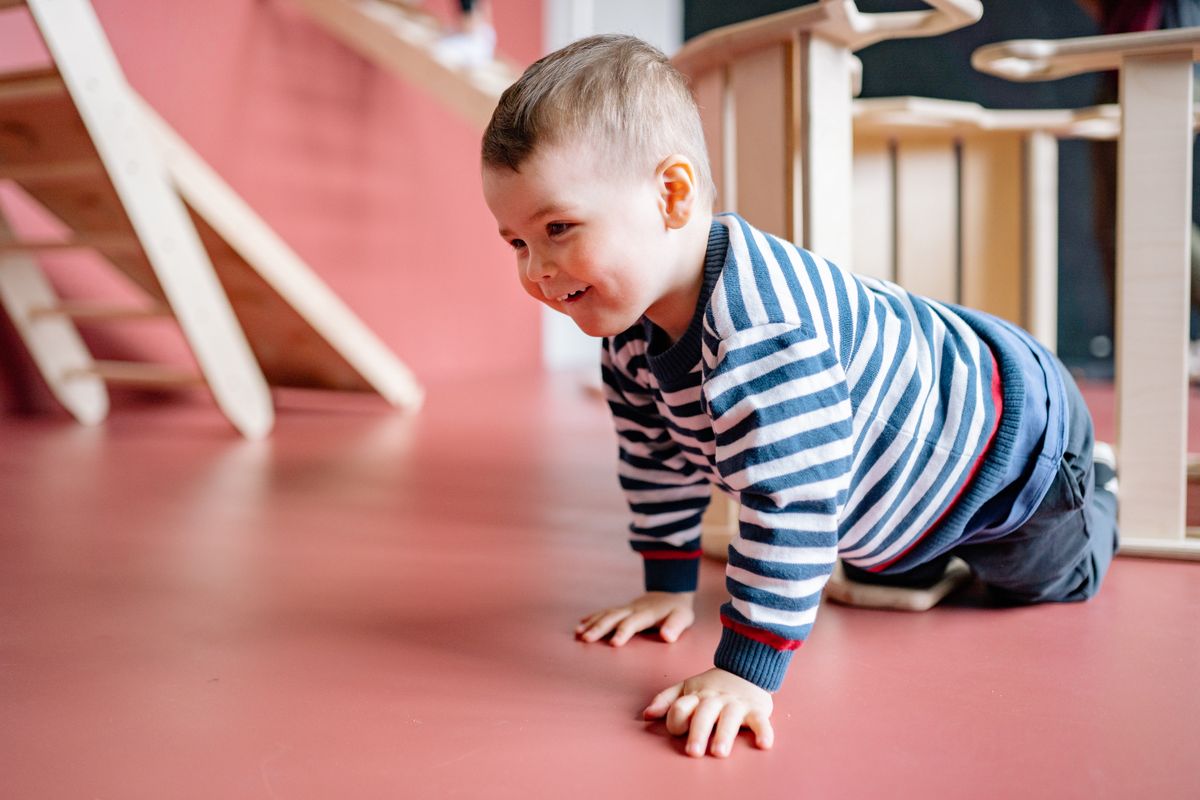 A child doing a bear crawl across the floor during active play