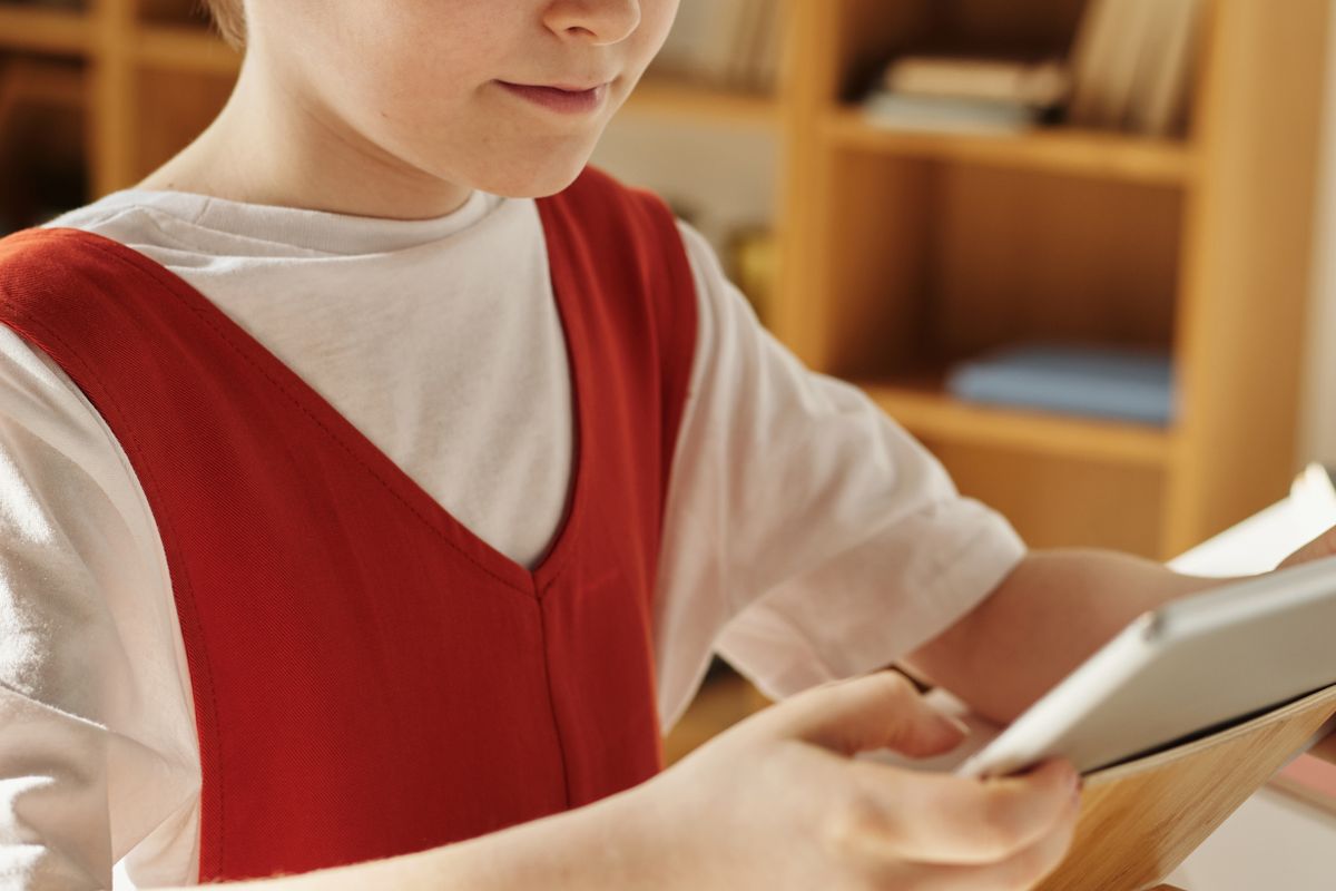 A child using a tablet with a communication app at a table