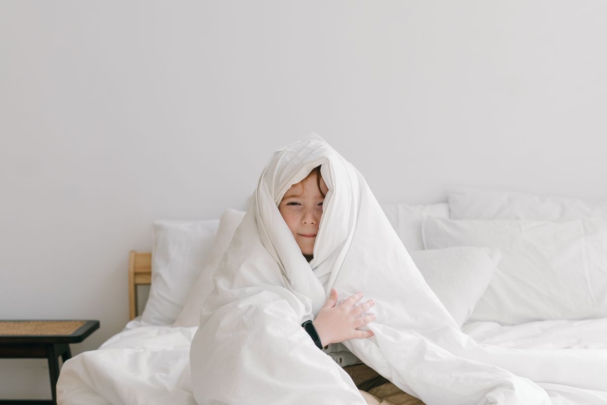A cosy, low-lit corner with soft cushions and a blanket where a child can decompress